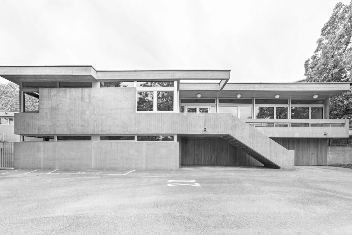 Die Betonfassade erscheint nach einer umfangreichen Sanierung wieder in ihrem ursprünglichen, rohen Sicht-Charakter und bildet zusammen mit den Holz-Metall-Fenstern in Aluminium das robuste Kleid des Hauses. 1_Verkehrsgarten_Nordfassade_Lukas_Raeber_Architekten_%C2%A9Weisswert_ms_1